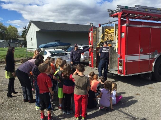 Firefighter with fire truck and group of children
